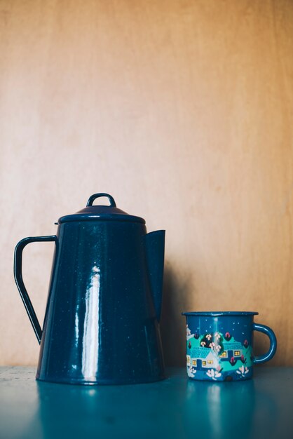 Ornamental porcelain teapot and mug against wooden backdrop