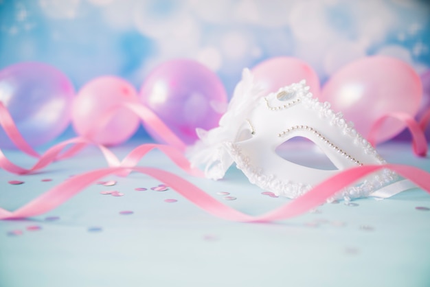 Free photo ornamental white mask in pink streamers