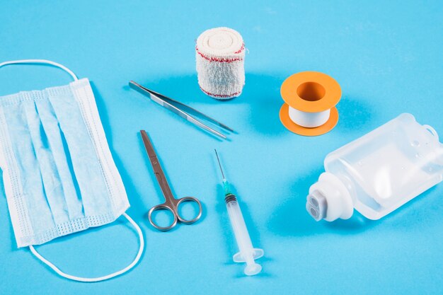 Orthopedic bandage; tweezers; mask; syringe and iv bottle on blue background