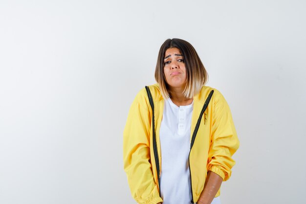 Ortrait of lady frowning face, curving lower lip in t-shirt, jacket and looking innocent front view