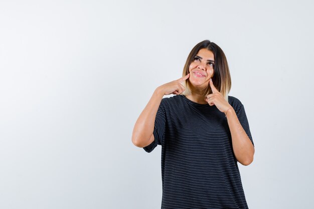 黒のTシャツで頬に指を置き、夢のような正面を見る女性のOrtrait