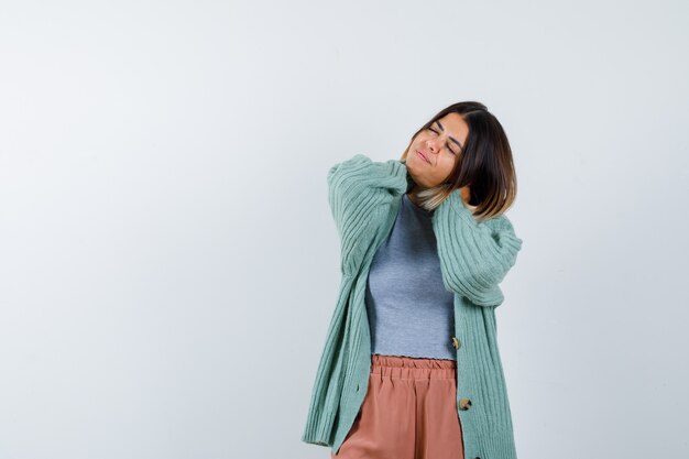 Ortrait of lady keeping hands on neck in casual clothes and looking relaxed front view