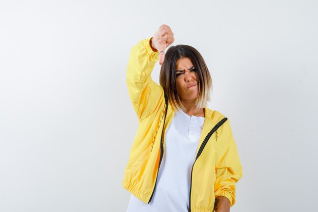 Ortrait of lady showing thumb down in t-shirt, jacket and looking displeased front view