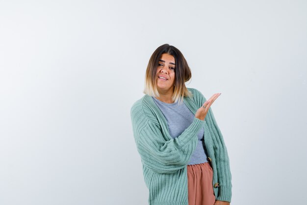 Ortrait of woman showing something in casual clothes and looking cheery front view