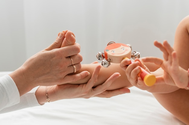 Osteopathist treating a baby girl who's playing with a wooden doll