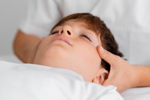 Osteopathist treating a child by massaging his head