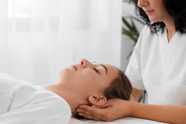 Osteopathist treating a female patient by massaging her face