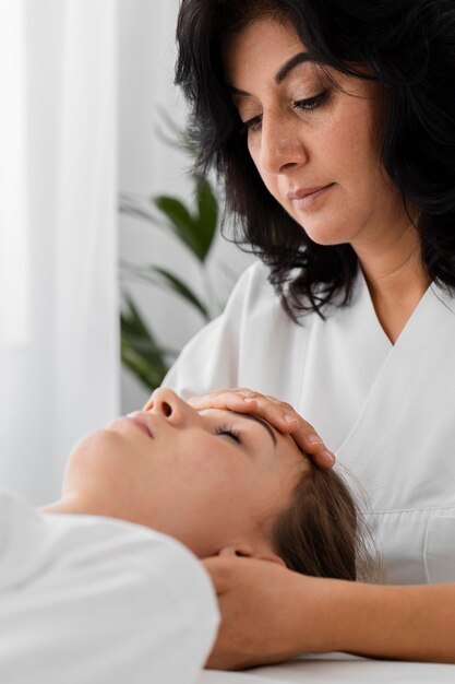 Osteopathist treating a female patient by massaging her face