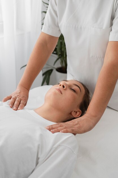 Osteopathist treating a female patient by massaging her shoulders