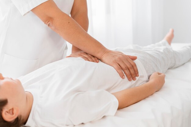 Osteopathist treating a kid by massaging his body