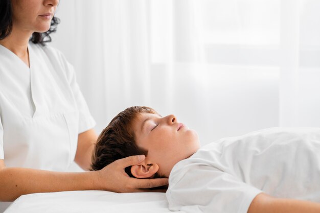 Osteopathist treating a kid by massaging his head