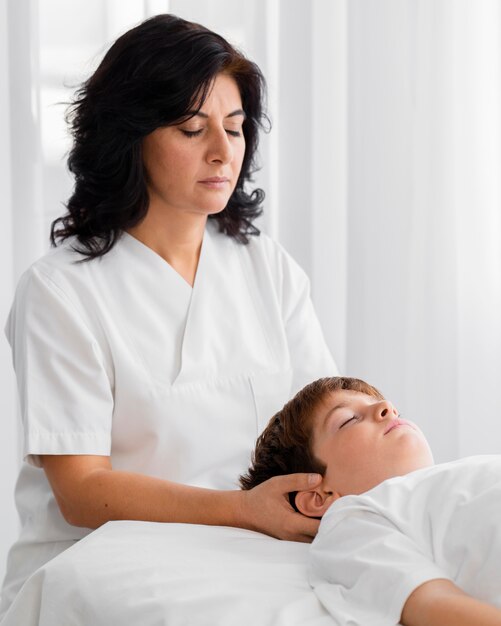 Osteopathist treating a kid by massaging his head