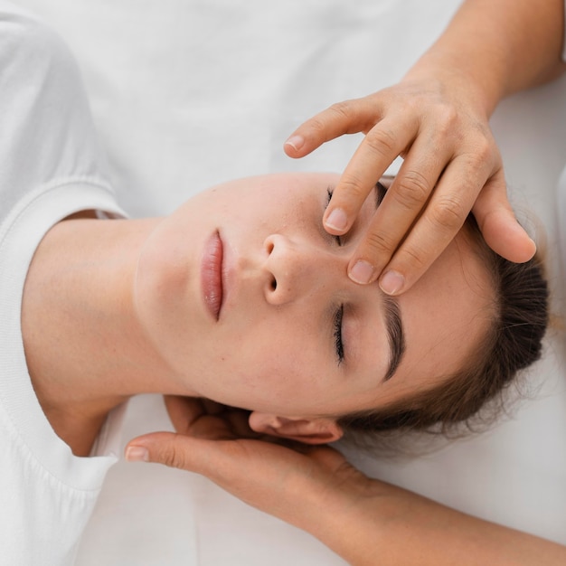Osteopathist treating a patient by massaging her face