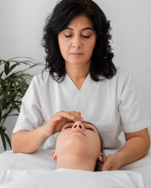 Osteopathist treating a patient by massaging her face