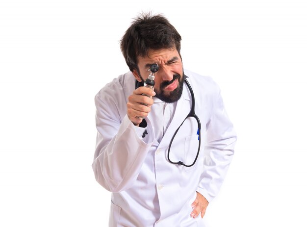 Otorhinolaryngologist with his otoscope over white background