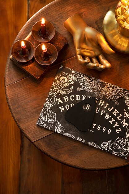 Ouija board and lit candles arrangement flat lay