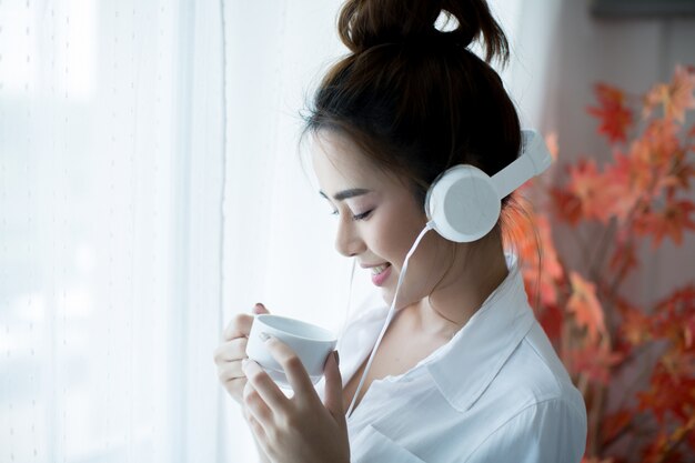 oung beautiful woman in bright outfit enjoying the music at home