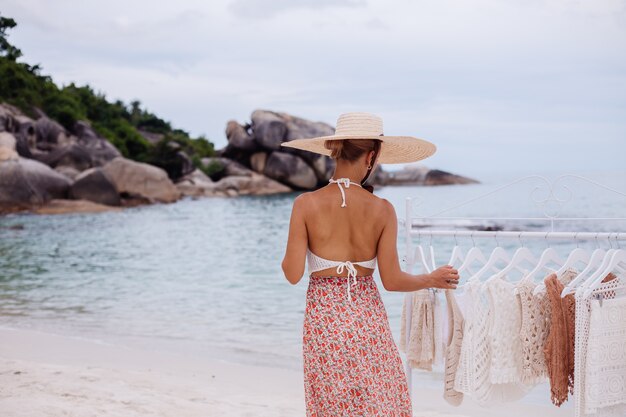 Открытый пляжный магазин вязаной одежды Выбор женщины, что купить на напольной вешалке Концепция летнего трикотажа