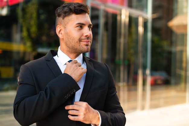 Outdoor businessman arranging his tie