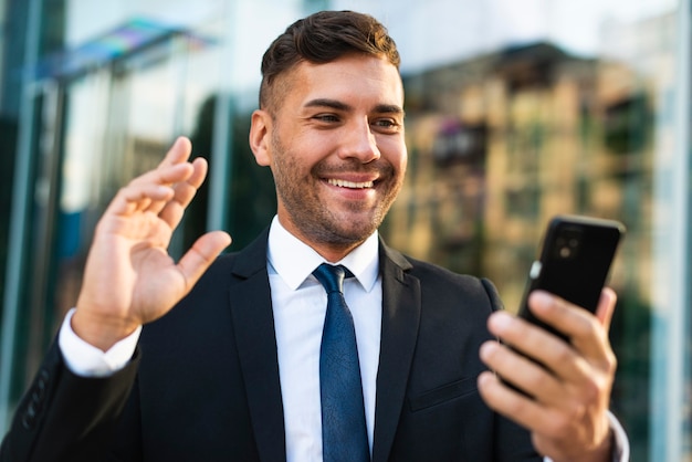 Outdoor businessman holding phone and smiles