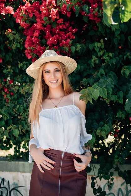 Outdoor close up portrait of young beautiful fashionable girl posing near blooming tree with flowers.