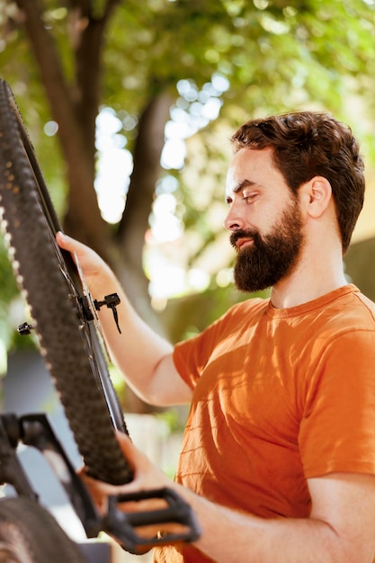 Outdoor detailed shot of caucausian man securing and adjusting bike tire rubber for annual maintenance. Healthy male cyclist dismantling damaged bicycle wheel to repair with expert work tool for cycli