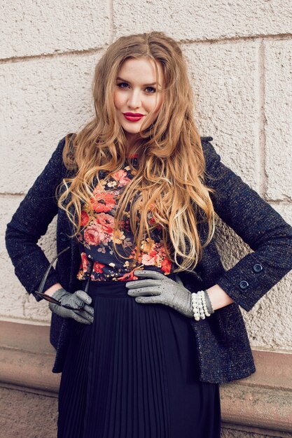 Outdoor fashion portrait of beautiful stylish girl posing at the street at elegant stylish coat dress and pumps, have long ginger hairs and perfect matched accessorizes .