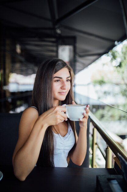 차 커피를 마시는 아름 다운 젊은 여자의 야외 패션 초상화
