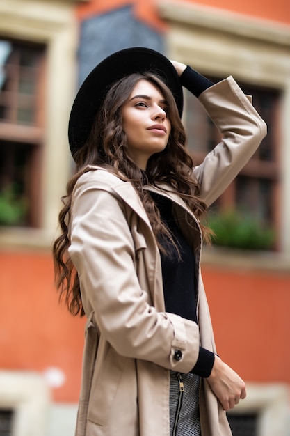 トレンディな秋の服と黒い帽子を身に着けている魅力的な官能的な若いスタイリッシュな女性の屋外ファッションの肖像画