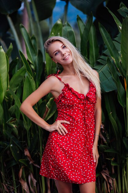 Outdoor fashion portrait natural beauty young pretty woman with light make up, star earings, bracelet and ring. Female in red summer flower dress