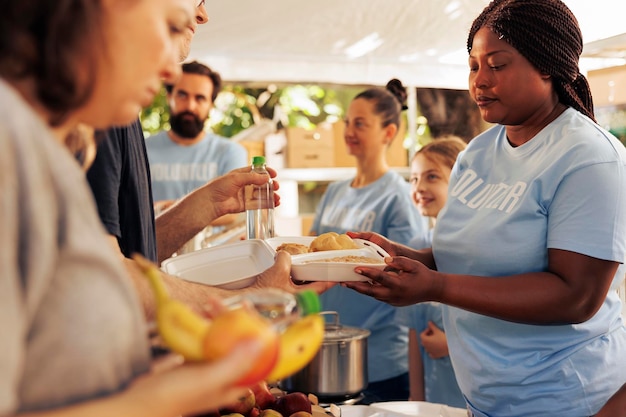 Foto gratuita evento di raccolta alimentare all'aperto con volontari di diverse etnie al servizio dei senzatetto, sottolineando l'importanza della lotta alla fame e alla povertà. aiutatori di beneficenza distribuiscono cibo gratuito ai bisognosi.