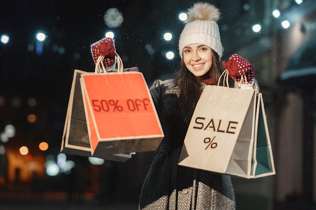 Free photo outdoor night portrait of young woman with shopping bags