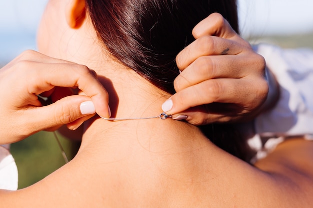 Outdoor portrait of asian woman's back wearing necklace.