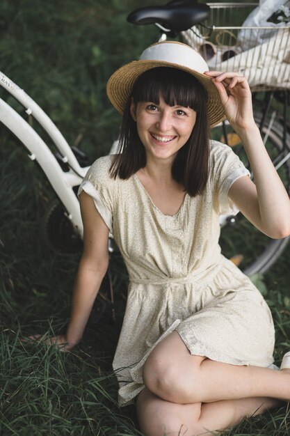 Outdoor portrait of attractive young brunette in a hat on a bicycle.