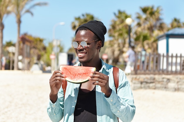 Free photo outdoor portrait of attractive young student holding slice of ripe juicy watermelon