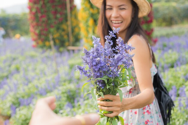 美しい中年のアジア女性の屋外のポートレート。花を持つフィールドで魅力的な女の子