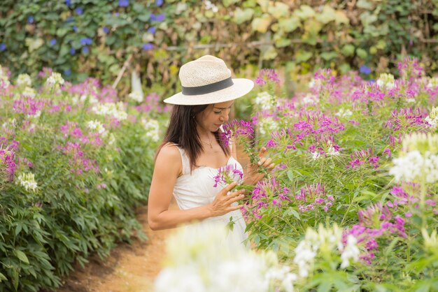 美しい中年のアジア女性の屋外のポートレート。花を持つフィールドで魅力的な女の子