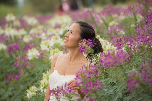 美しい中年のアジア女性の屋外のポートレート。花を持つフィールドで魅力的な女の子