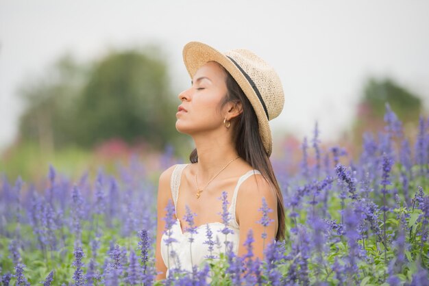 美しい中年のアジア女性の屋外のポートレート。花を持つフィールドで魅力的な女の子