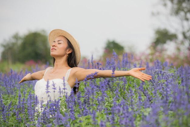 美しい中年のアジア女性の屋外のポートレート。花を持つフィールドで魅力的な女の子