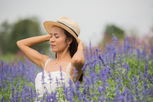 美しい中年のアジア女性の屋外のポートレート。花を持つフィールドで魅力的な女の子