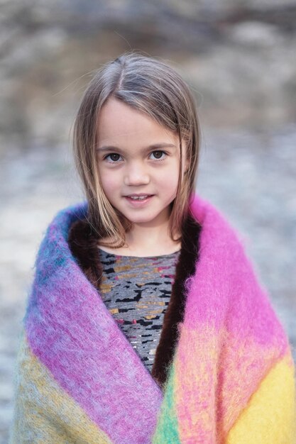 Внешний портрет милой маленькой девочки, завернутой в теплое красочное одеяло.