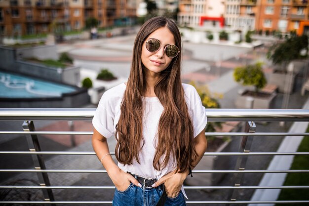 Outdoor portrait of cute young woman on bridge in european city.