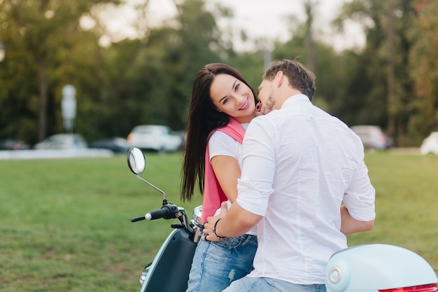 Outdoor portrait from back of man in white shirt embracing woman with black hair