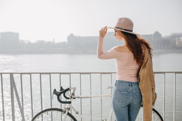 秋の日の橋から街の景色を楽しむ明るい化粧のかわいい巻き毛の女性 無料の写真