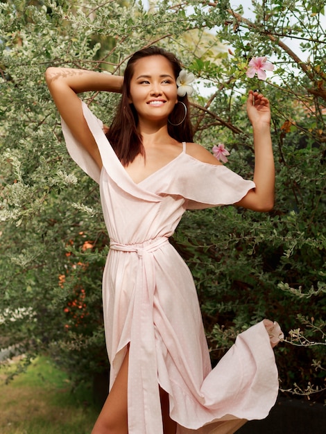 Outdoor portrait of lovely happy Asian female posing in summer park.