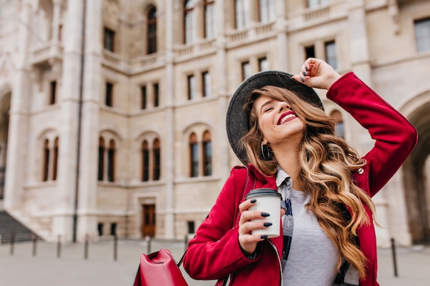 Outdoor portrait of magnificent woman with leather backpack laughing