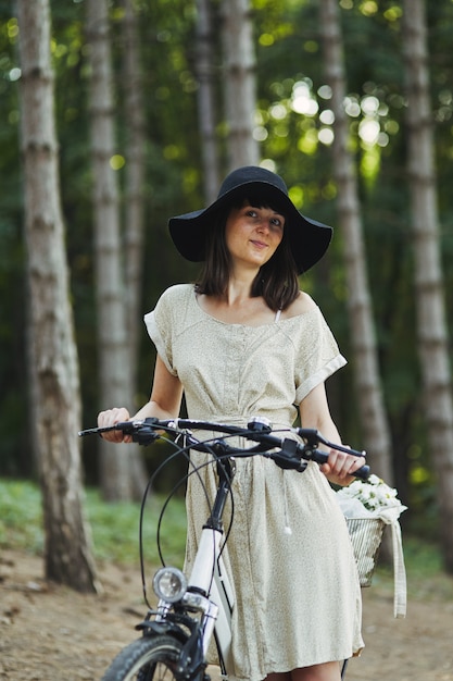 Бесплатное фото Внешний портрет привлекательного молодого брюнет в шляпе на велосипеде.