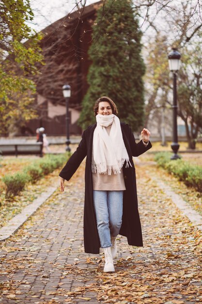 Outdoor portrait of woman in park wearing winter black coat and white scarf