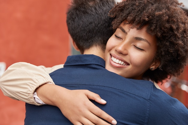 Outdoor shot of best friends embrace warmly each other